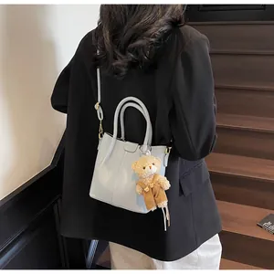 Detail of light blue lychee pattern leather shoulder bag with a cute bear charm pendant