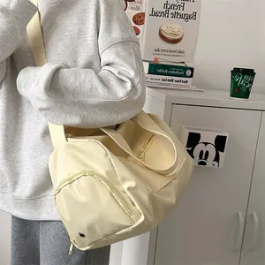Detail view of the beige multi-purpose travel bag with side zipper and strap