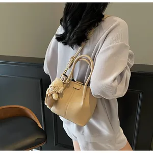 Close-up of beige lychee texture handbag with cute plush bear pendant accessory