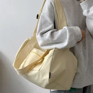 Side view of cream canvas tote bag showing wide shoulder strap and outer zipper pocket