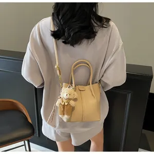 Detail showing apricot faux leather bag with bear charm and adjustable shoulder strap