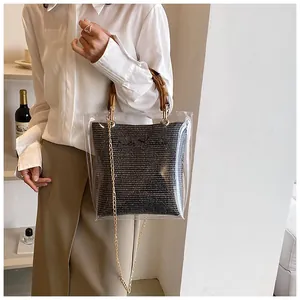 Detail of transparent tote bag with bamboo handle and black woven inner pouch shown on model