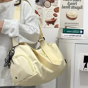 Detail of a large cream yellow gym bag showing the texture, side zip, and bear charm