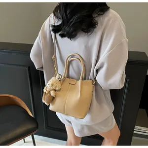 Beige bucket bag with lychee grain texture and a cute brown plush bear charm detail