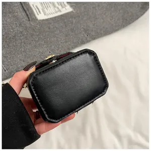 Détail du mini sac en cuir noir avec fermoir fleur dorée et doublure rouge vif