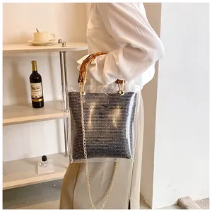 Detail of transparent PVC handbag with bamboo handle, straw pouch and gold chain
