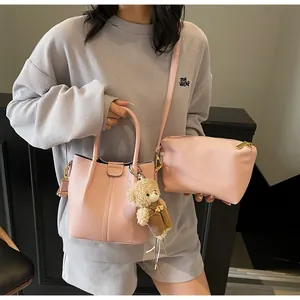 Pink textured leather bucket bag featuring a cute plush bear charm and crossbody strap