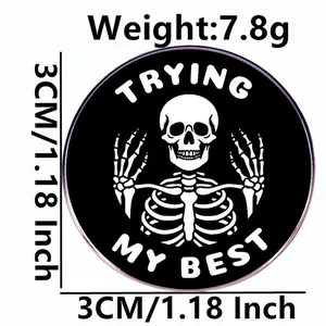 Inspirational skeleton badge in black enamel with white 'TRYING MY BEST' text, 3cm size