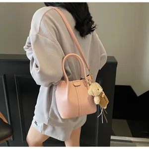 Detail of pink bucket bag with lychee grain texture and cute plush bear charm accessory