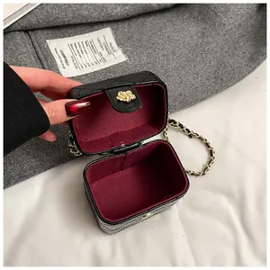 Détail du mini sac boîte matelassé avec doublure rouge et fermoir fleur dorée