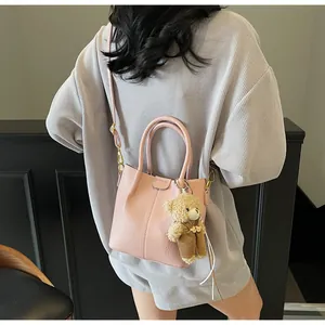 Detailed shot of pink lychee leather handbag with a plush bear charm on its side