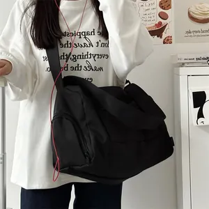 Detail view of large black gym bag showing a separate side zipper compartment for storage