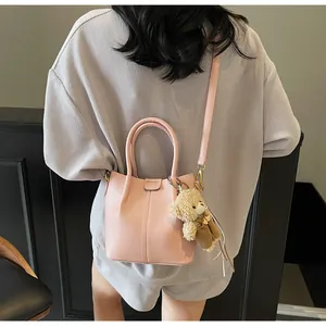 Pink bucket bag with pebble leather texture and a cute brown plush bear charm