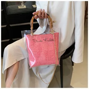 Close-up of clear PVC tote with pink woven inner bag and vintage bamboo style handle