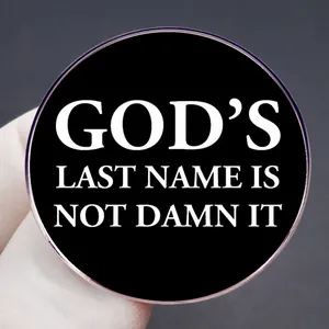 Pin redondo divertido con texto 'GOD'S LAST NAME IS NOT DAMN IT' en blanco y negro