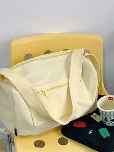 Detail view of cream-yellow gym bag with zipper pockets and wide strap on a chair