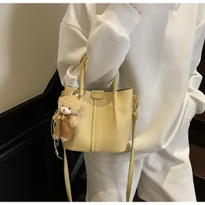 Detail of creamy yellow bucket bag with lychee texture and cute bear charm pendant