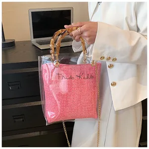 Close-up of transparent tote with bamboo handle, pink woven insert and metal chain strap