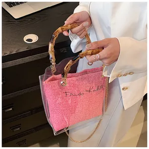 Close-up of pink woven interior and bamboo handle on transparent PVC handbag