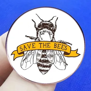 Save The Bees brooch with bee sketch and yellow ribbon on a blue textured background