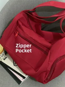 Detail of a large red sports bag showing a functional side zipper pocket on nylon fabric