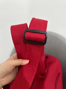 Detail of red travel bag featuring wide reinforced shoulder straps and adjustable buckles