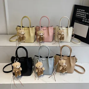 Minimalist bucket shoulder bags in six colors with bear charms on marble steps