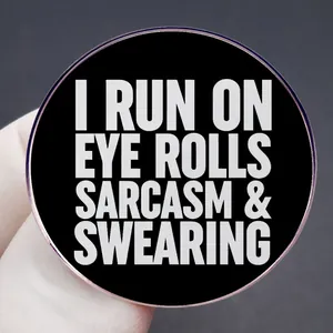 Spilla in smalto con scritta 'I RUN ON EYE ROLLS SARCASM & SWEARING' in bianco e nero