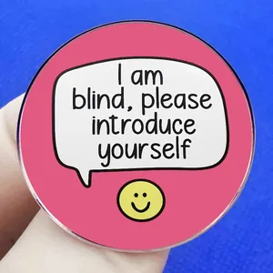 Badge rond rose avec texte I am blind please introduce yourself et icône de smiley jaune