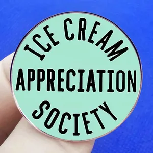 Mint green Ice Cream Appreciation Society metal pin badge held against blue fabric