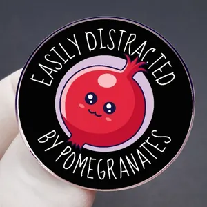 Funny Pomegranate Enamel Pin with Easily Distracted text on round black metal badge