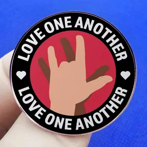 Broche ronde Love One Another avec mains en langue des signes sur fond rouge élégant