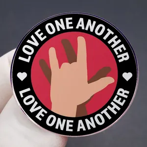 Pin's Love One Another avec tons de peau divers et signes de main Je t'aime sur fond rouge