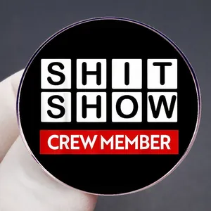 Chapa metálica Shit Show Crew Member con texto blanco sobre fondo negro y rojo intenso
