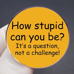 Funny yellow enamel pin with 'How stupid can you be?' quote on a gray background