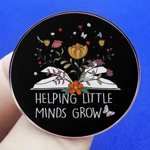 Enamel pin with flowers and book featuring Helping Little Minds Grow inspirational text