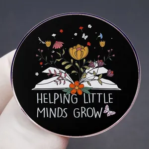Round enamel pin with flowers growing from a book and Helping Little Minds Grow text