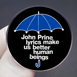 Spilla rotonda in smalto con ombrello blu e testo di John Prine su fondo nero