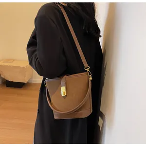 Detail of brown matte bucket bag showing the sleek gold buckle and suede texture