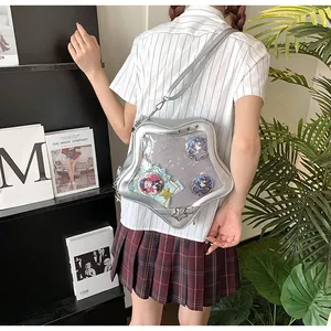Close-up of a silver star-shaped ita bag featuring a clear PVC window and anime pins