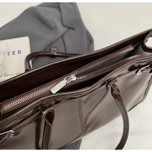 Detail view of the smooth dark brown leather tote bag with a silver zipper closure