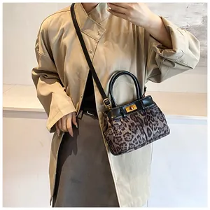 Close-up of leopard print handbag with gold hardware lock worn with a beige coat