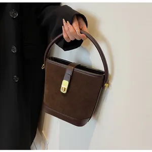 Detail of retro coffee bucket bag with matte suede texture and gold metal clasp