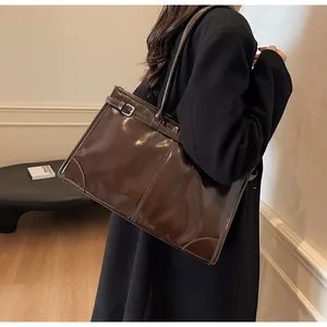 Chocolate brown tote bag with silver buckle and belt detail shown on model's shoulder