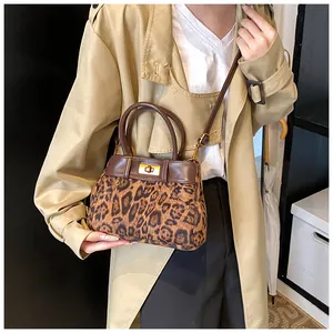 Detail of leopard print handbag with brown leather handles and golden twist lock