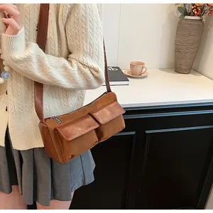 Detail view of brown suede and leather crossbody bag with dual utility pockets and zippers