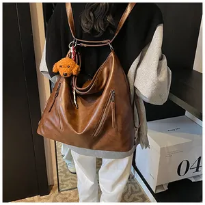 Detail of vintage brown leather backpack with dual zippers and cute teddy plush charm
