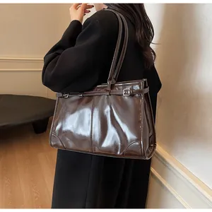 Close-up of a large vintage tote bag in dark brown glossy leather with adjustable strap