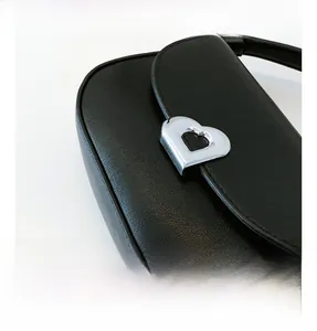 Close-up of black textured leather bag with heart-shaped silver metal buckle detail