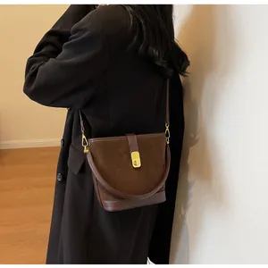 Close-up of matte brown bucket bag featuring gold buckle and leather拼接 texture